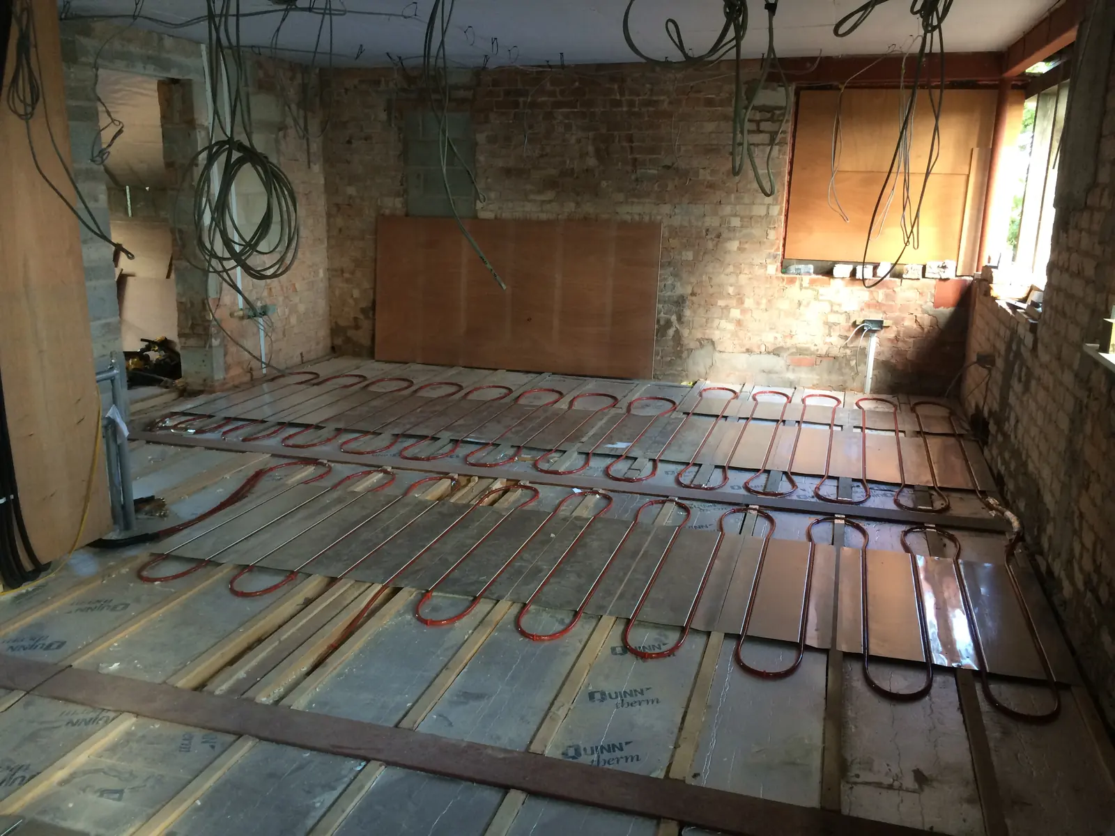 Underfloor heating pipe on metal spreader plates between timber joists