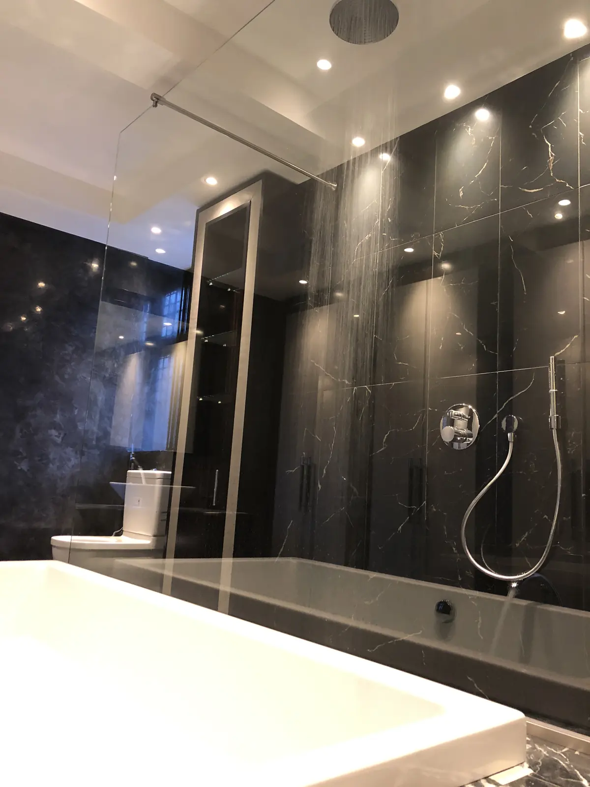 Bathroom in black marble with a rainfall shower, a handheld shower and a wall-hung toilet